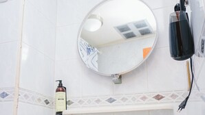 A bathroom with a white sink, a mirror, and a shelf with toiletries. - ELDEPTO LA SERENA (Coquimbo)