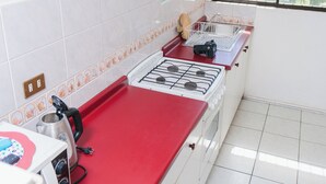 A kitchen with a red countertop, white cabinets, and a gas stove. - ELDEPTO LA SERENA (Coquimbo)