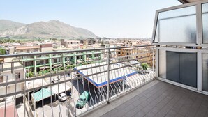 Un balcón con vistas a una zona residencial, que incluye edificios y una montaña al fondo.