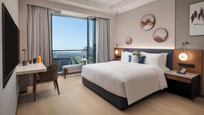 Una habitación de hotel moderna con una cama grande, un escritorio y vistas a la ciudad.