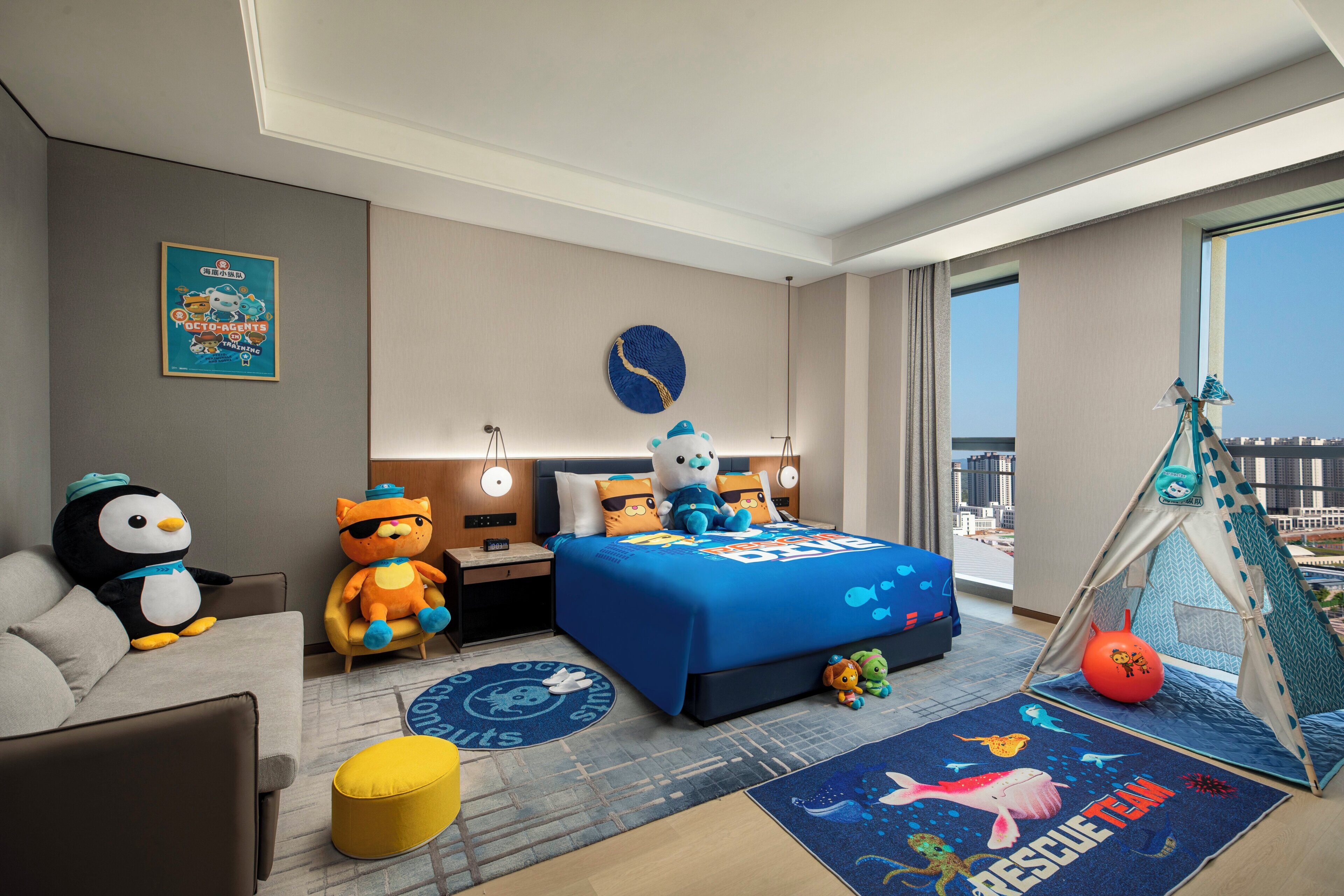 Habitación de hotel con cama, sofá, tienda de juegos y un amplio ventanal con vistas a la ciudad.