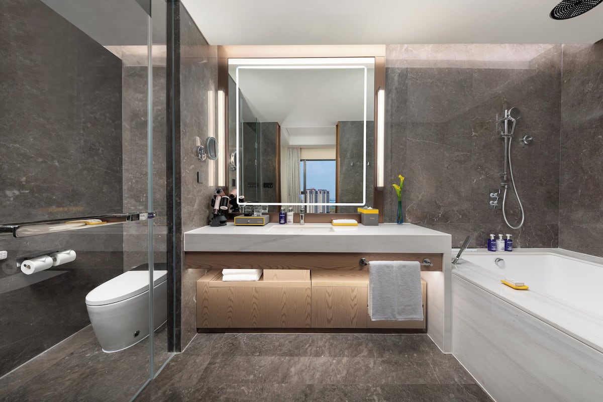 Un baño moderno con ducha de vidrio, un espejo grande y una bañera.