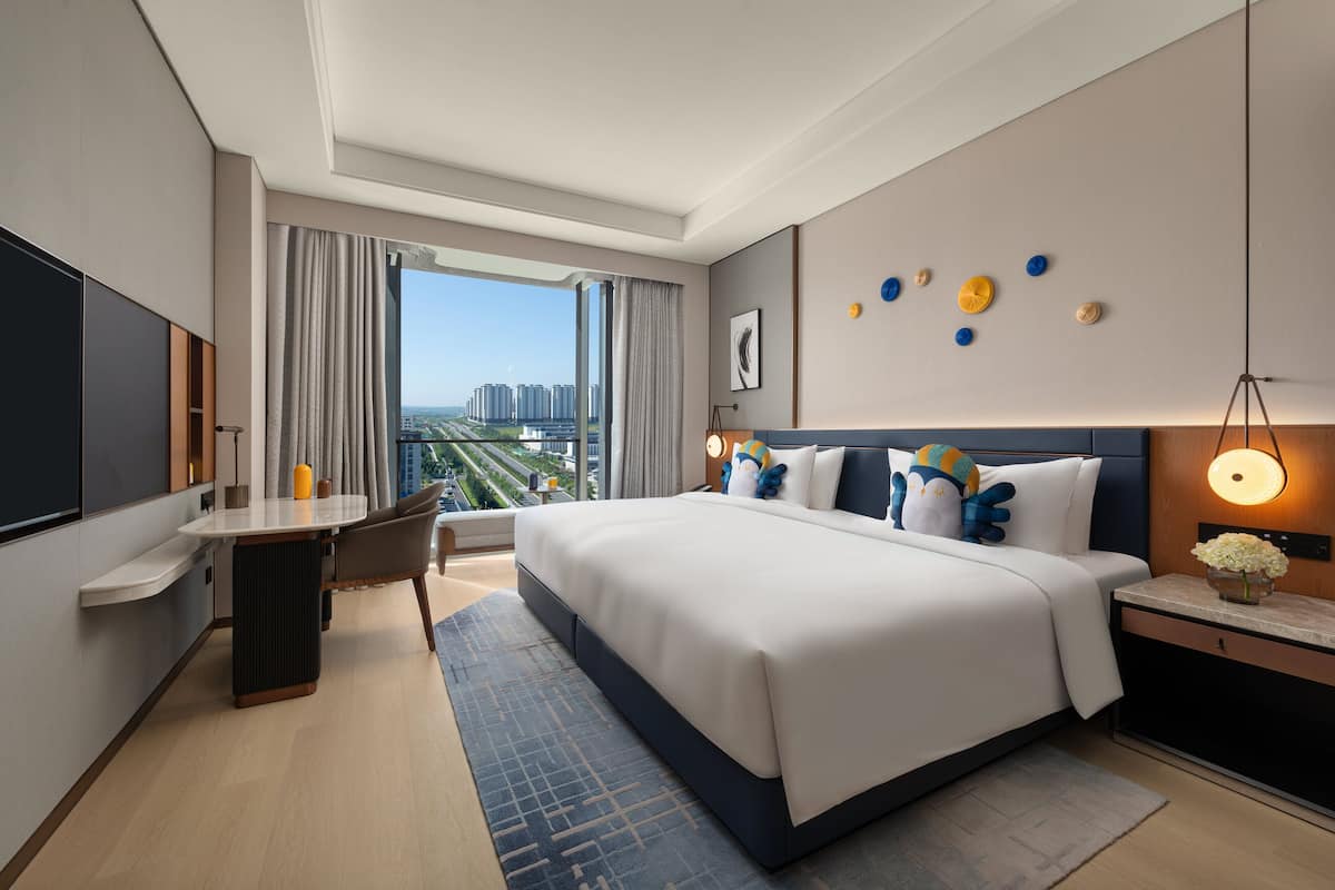 Una habitación de hotel moderna con una cama grande, un escritorio y vistas a la ciudad.
