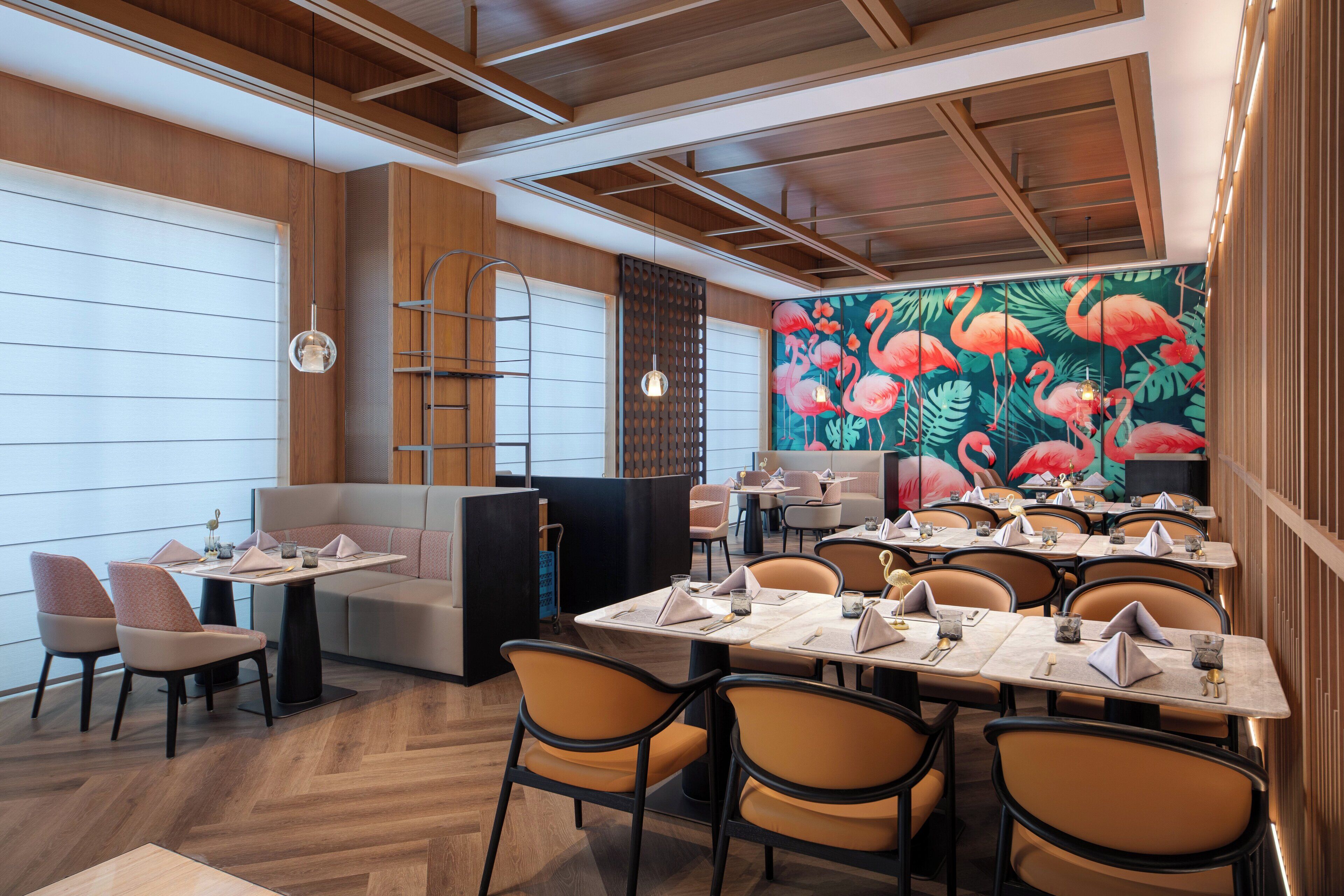 A restaurant with wooden paneling, a mural of flamingos, and a variety of seating options including tables and booths.