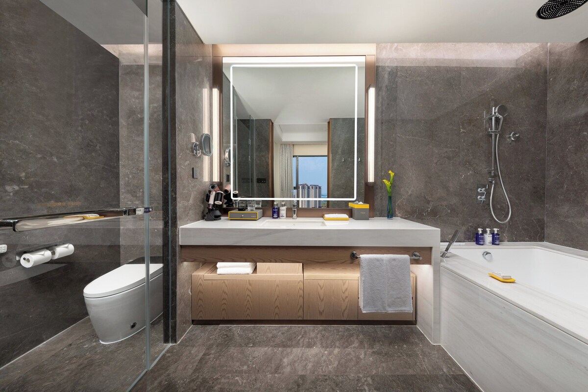 A modern bathroom with a glass-enclosed shower, a large mirror, and a bathtub.