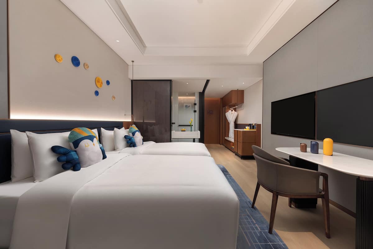 Una habitación de hotel moderna con una cama grande, un escritorio y una televisión.