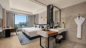 Una habitación de hotel moderna con una cama grande, un escritorio, una tocador con espejo y vistas a la ciudad.