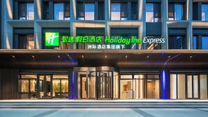 Un hotel Holiday Inn Express amb façana moderna, grans finestres i una entrada destacada amb una porta giratòria.