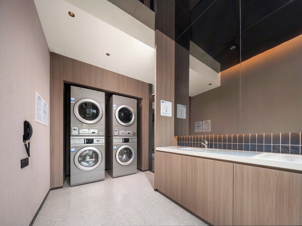 A modern hotel bathroom with two stacked washing machines, a sink, and a mirror. - Holiday Inn Express Beijing Mentougou by IHG (Mentougou)