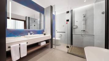 Un baño moderno con ducha envuelta en cristal, una bañera blanca y un espejo grande sobre el lavabo.
