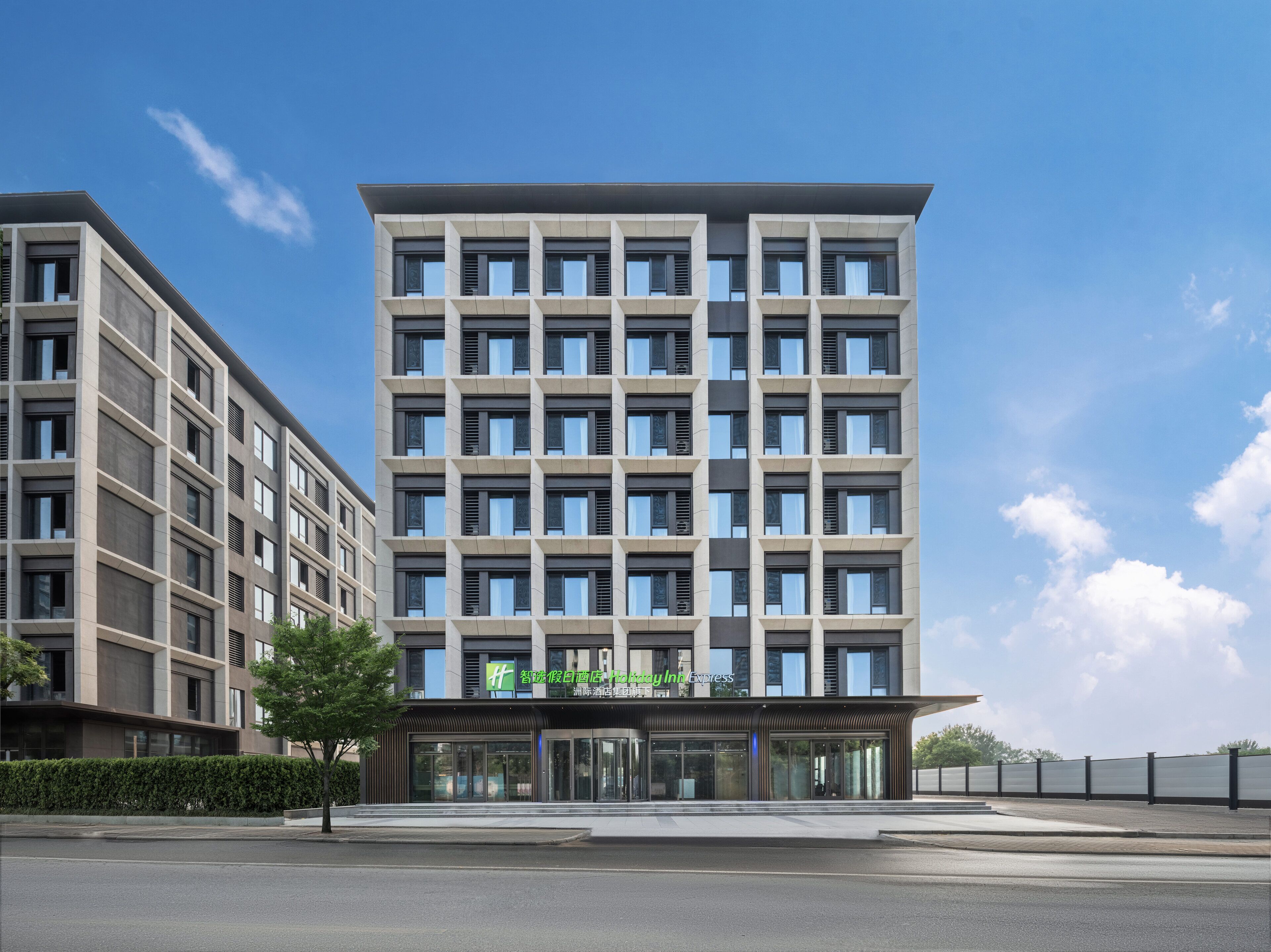 Un hôtel moderne, avec une façade symétrique, de nombreuses fenêtres et une entrée imposante dotée de portes en verre.