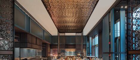 A spacious dining area with high ceilings and modern decor, featuring multiple tables and chairs arranged for dining.
