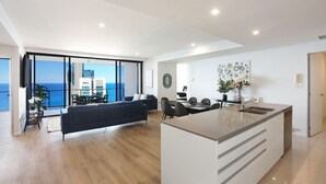 A modern hotel room with a balcony, a dining area, and a kitchen.