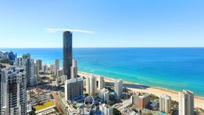A coastal cityscape with high-rise buildings, a beach, and a clear blue sky.