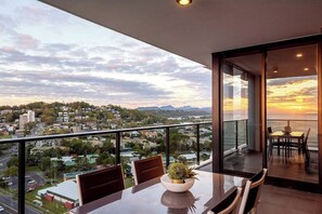 Enjoy a city view from the balcony with a dining table and potted plant.