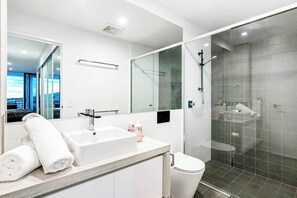 Enjoy a refreshing shower in the bathroom with a sink, glass-enclosed shower, and city view.