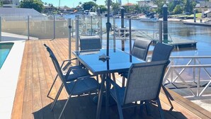 A deck with a table and chairs, an umbrella, and a view of a marina with boats.