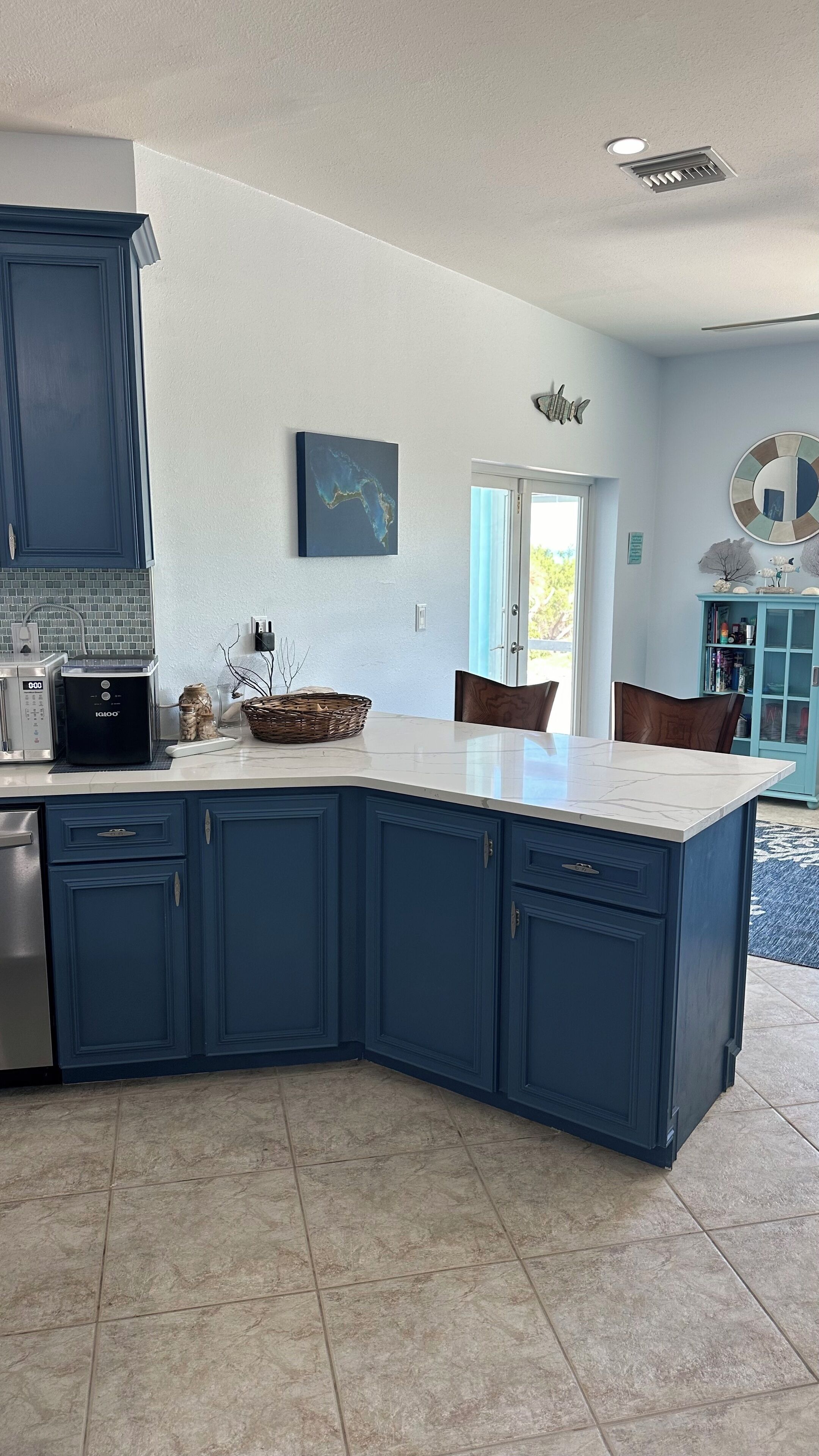 A modern kitchen with blue cabinets, a white countertop, and a built-in dishwasher.