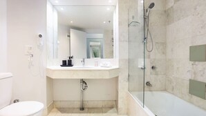 A modern bathroom with a glass-enclosed shower, a white toilet, and a vanity with a mirror. - NEW Central Surfers Studio Apartment. (Surfers Paradise)