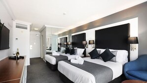 A hotel room with two beds, a TV, a desk, and a chair.