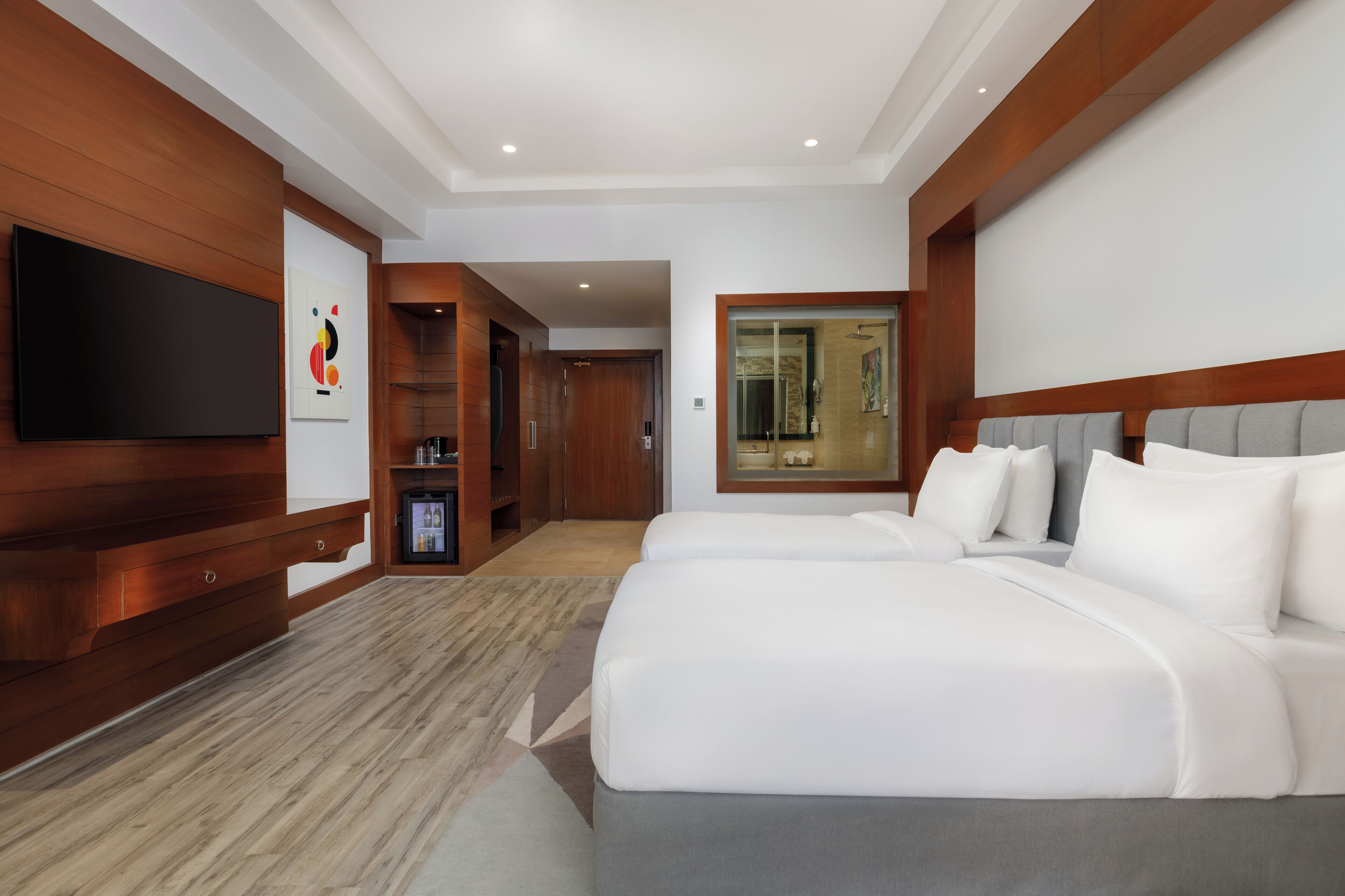 A hotel room with a large bed, a TV, wooden paneling, and a modern design.