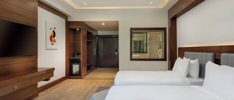A modern hotel room with two beds, a TV, a wooden cabinet, and a painting on the wall.