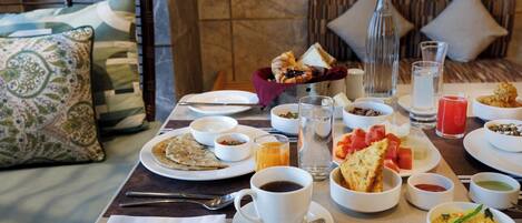 Una mesa de desayuno servida con diferentes platos, como tostadas, fruta y bebidas.