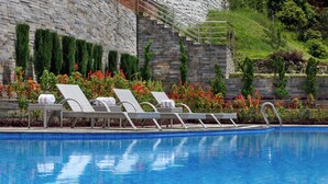 A swimming pool with lounge chairs and a stone wall. - Holiday Inn Resort Kathmandu Budhanilkantha by IHG (Burhanilkantha)