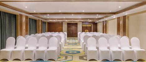 A conference room with rows of white chairs and a patterned carpet.