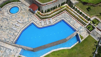 Relax by the pool surrounded by lush greenery and lounge chairs.