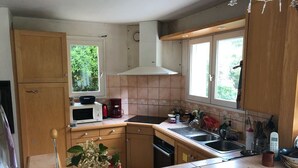 Cocina con armarios de madera, microondas, estufa y ventana que deja entrar luz natural.