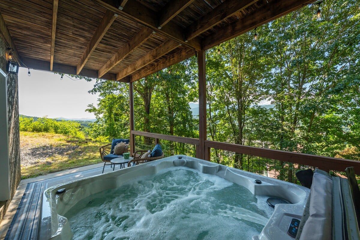 Un bain à remous doté d’une terrasse en bois et offrant une vue sur un paysage luxuriant.