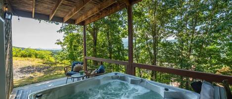 Un bain à remous doté d’une terrasse en bois et offrant une vue sur un paysage luxuriant.
