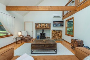 A cozy living room with a wooden coffee table, a sofa, a TV, and a fireplace. - Cozy Cabin in town with a View! Hot Tub+Grill+WiFi (Burnsville)