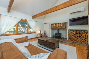 A cozy living room with a sofa, a coffee table, a fireplace, and a TV mounted on the wall.