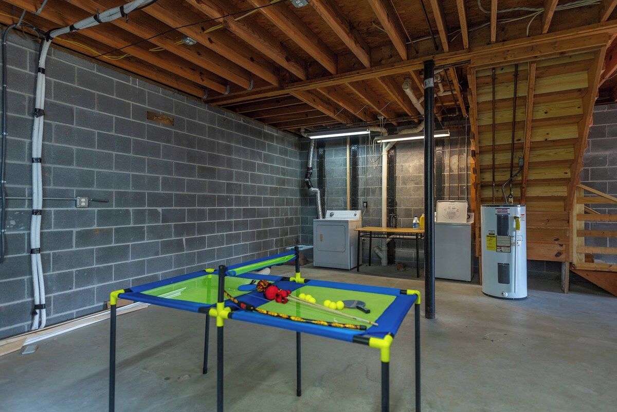 A room with a foosball table, a refrigerator, and a workbench.