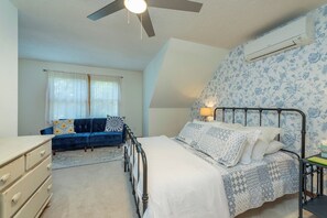 Ein Schlafzimmer mit einem Bett, einem Schminktisch, einem blauen Sofa und einem Deckenventilator.