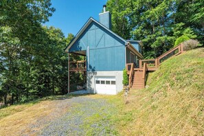 A house with a blue exterior, a garage, and a wooden staircase leading up to a deck.