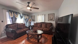 A living room with two sofas, a coffee table, a ceiling fan, and a television. - Charming 2-bedroom house with WiFi, AC in pleasant Meriden (Meriden)