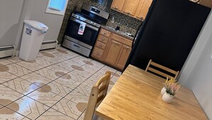 A kitchen with wooden cabinets, a stainless steel stove, and a black refrigerator. - Charming 2-bedroom house with WiFi, AC in pleasant Meriden (Meriden)