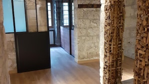 A hallway with stone walls, wooden flooring, and a black door. There is a wooden wall with carvings on the right. - Apartment Near French Alps (Serrieres-en-Chautagne)
