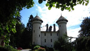 A castle with two towers, surrounded by greenery and a clear sky. - Apartment Near French Alps (Serrieres-en-Chautagne)