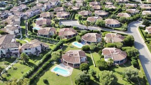 Een woonwijk met huizen met betegelde daken, keurig onderhouden gazons en een zwembad.