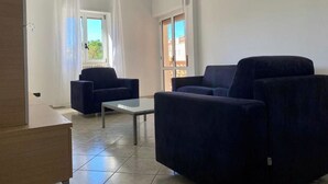 A living room with two dark sofas, a glass coffee table, and a wooden cabinet. - Three-Bedroom Apartment - Rosanna's House (Monopoli)