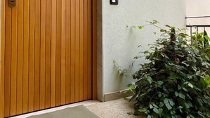 A wooden door with a metal handle, a small mat at the entrance, and a wall-mounted light fixture. - Three-Bedroom Apartment - Rosanna's House (Monopoli)