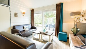 A modern living room with a sofa, coffee table, and a dining area with chairs. - Ameland Coastal Retreat (Hollum)