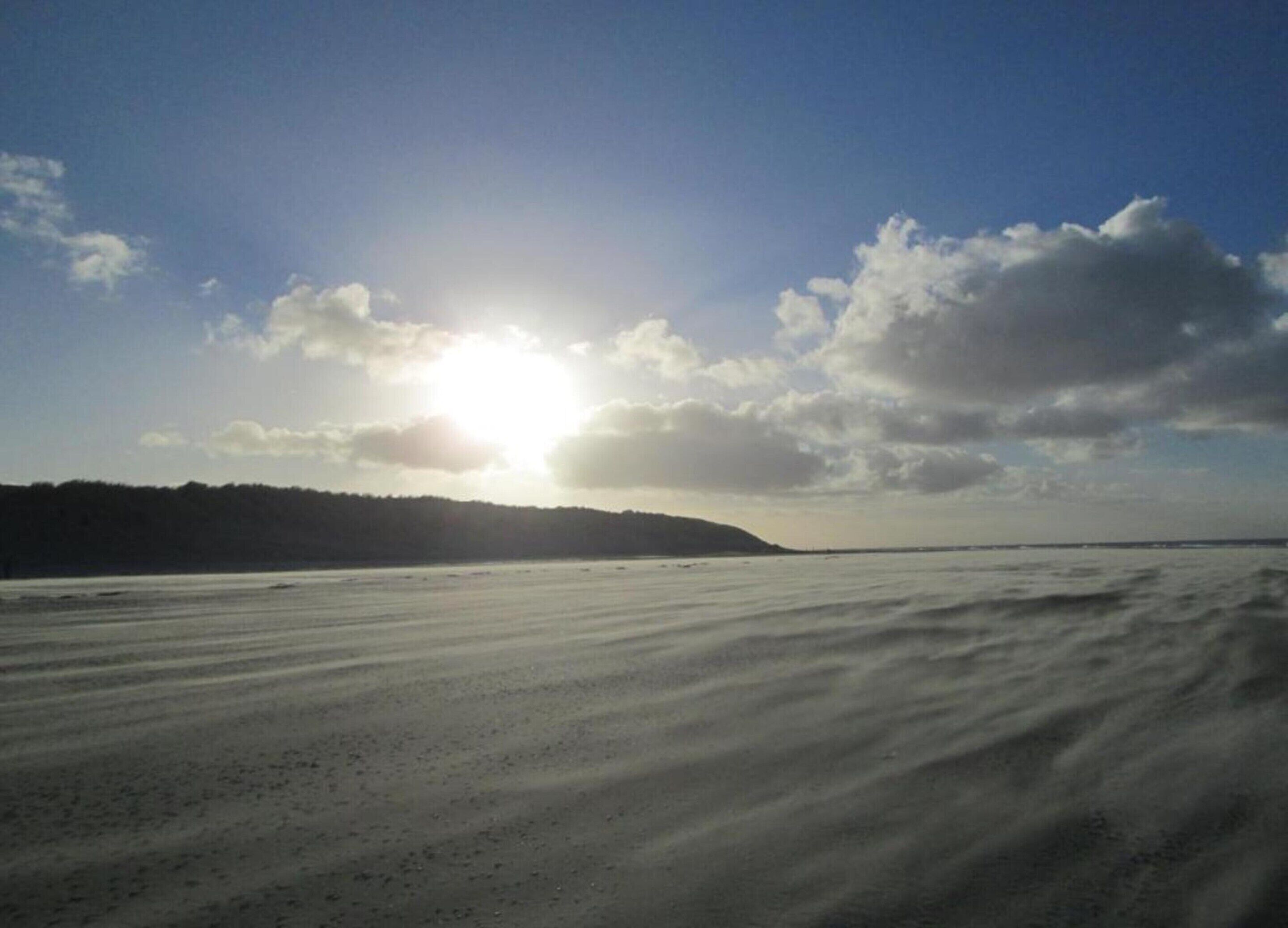 A beach with a clear sky and the sun shining.