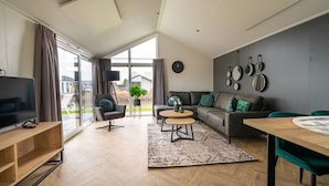 Uma sala de estar moderna com um sofá, poltronas, uma mesa de centro e uma televisão.