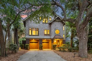A two-story house with a garage, surrounded by trees and a well-maintained lawn.