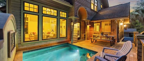 A house with a swimming pool, outdoor seating, and a covered patio area.